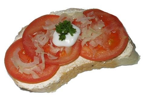 Chlebíček s plátky rajčat, ozdobené, cibulkou, kudrnkou a špičkou majonézového přelivu - velka je namazána máslem