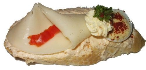 Chlebíček s dudáckou pomazánkou, sýrem eidam, plátkem kapie, kudrnkou, plátkem vajíčka a ozdobený máslovou špičkou